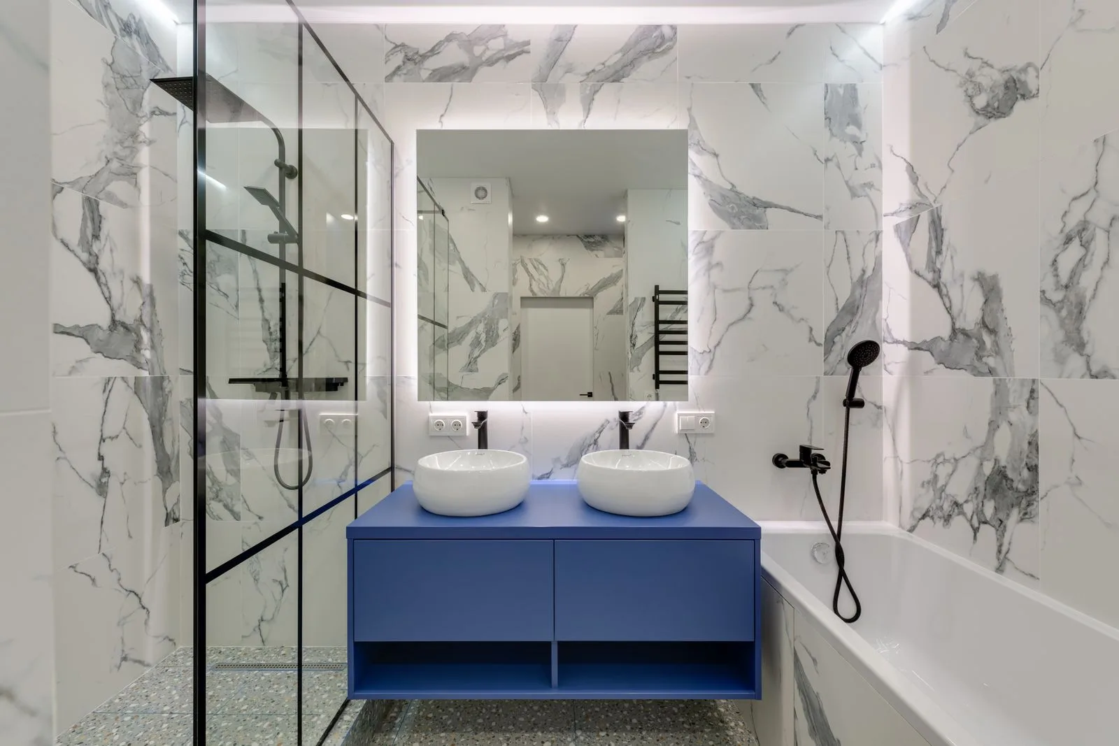 Salle de bains rénovée à Nice, murs effet marbre, double vasque et douche vitrée